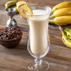 Glass Of Dirty Banana Cocktail With Ingredients On Wooden Background